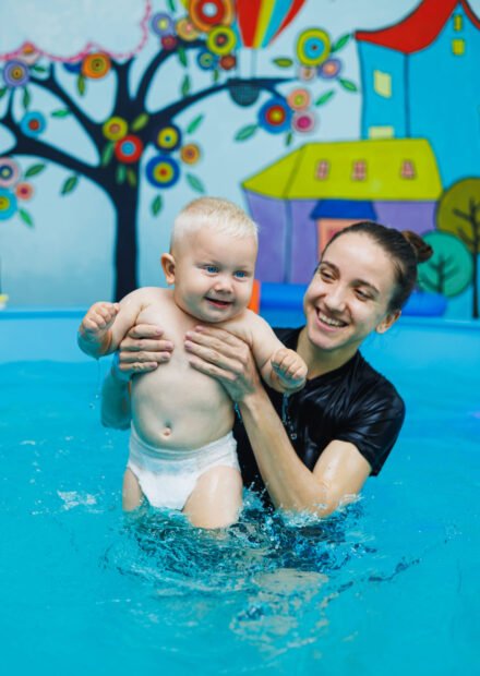 The boy has been swimming with a coach in the pool for one year. Teaching a child to swim. Swimming pool for children.